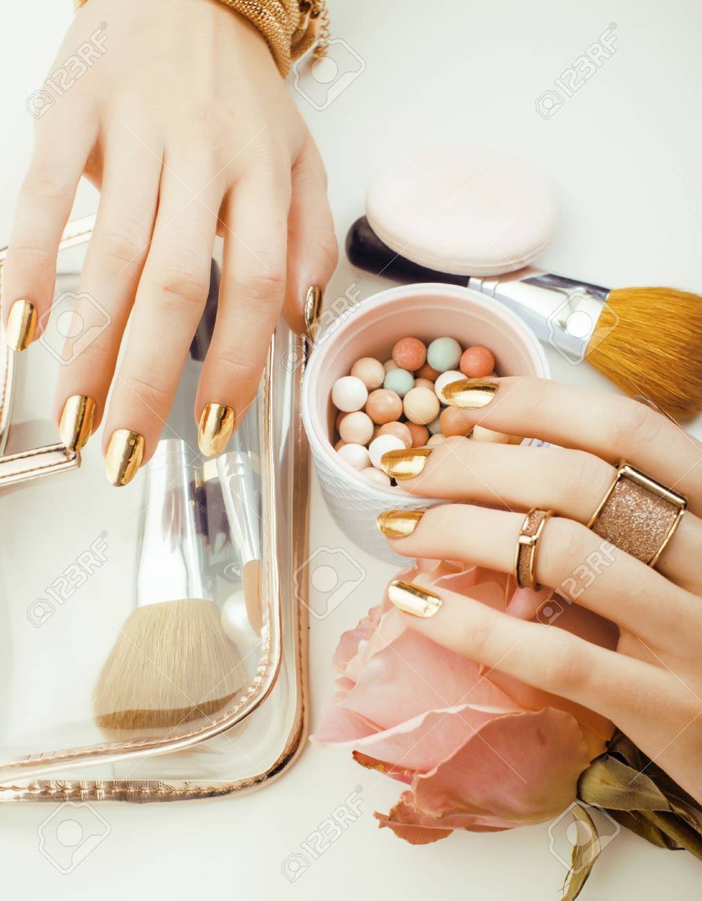 woman hands with golden manicure and many rings holding brushes