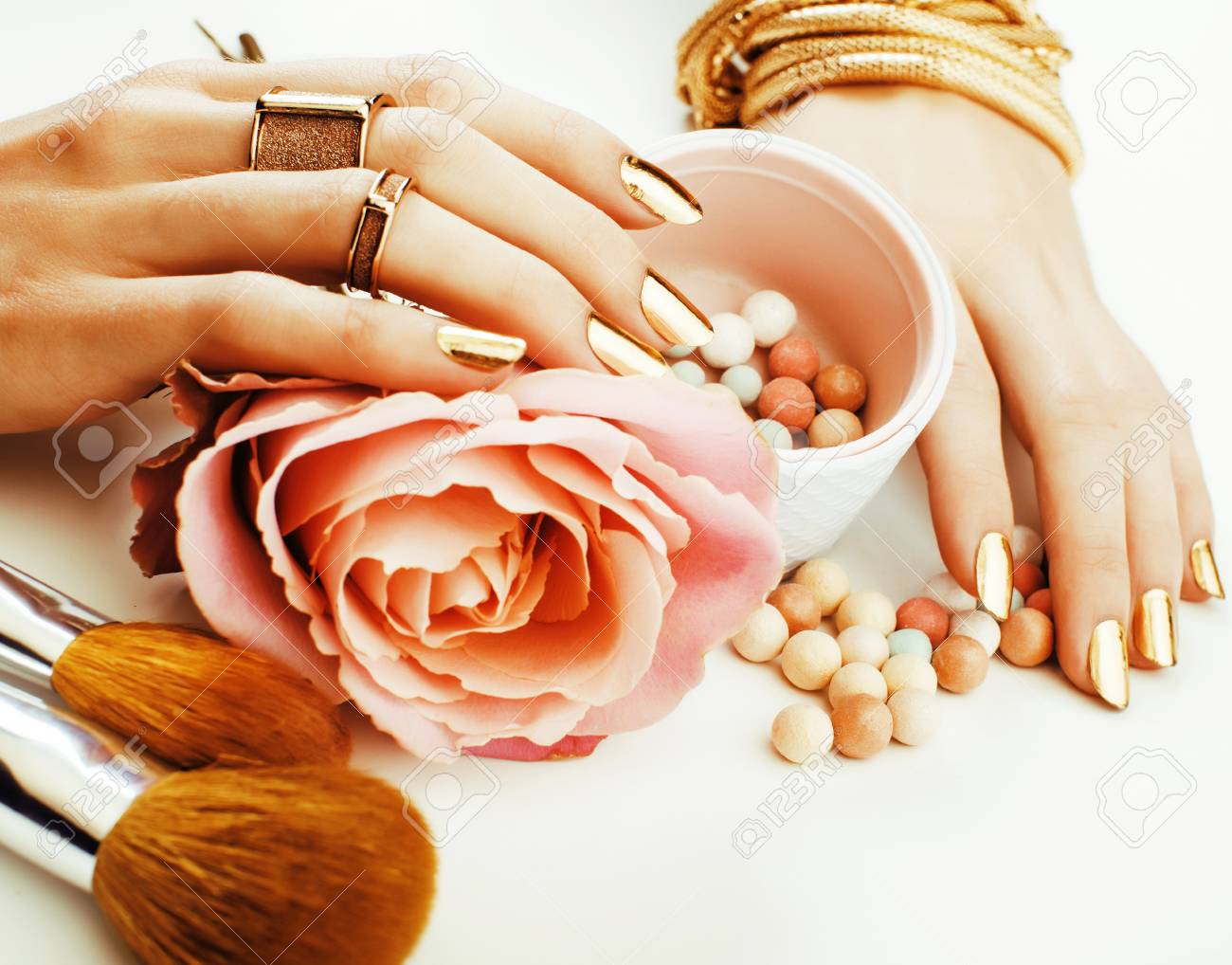 woman hands with golden manicure and many rings holding brushes