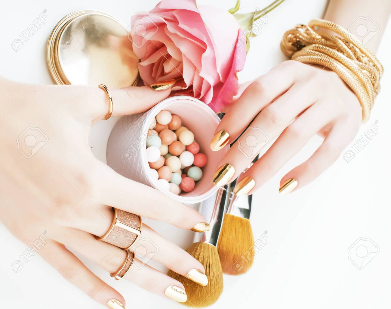woman hands with golden manicure and many rings holding brushes, makeup artist stuff stylish, pure close up pink flower rose among cosmetic for makeup - 143450788 woman hands with golden manicure and many rings holding brushes, makeup artist stuff stylish, pure close up pink flower rose among cosmetic for makeup - 143450788