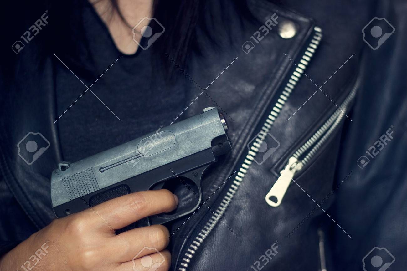 黒のジャケットのテクスチャ背景に手で銃を持つ女性 の写真素材 画像素材 Image