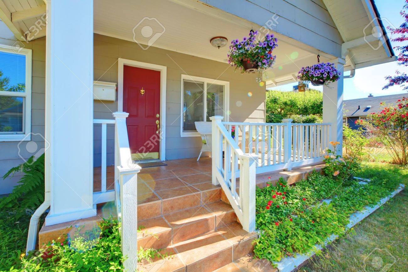 Grey House Porch With Red Door White Railings And Purple Flowers