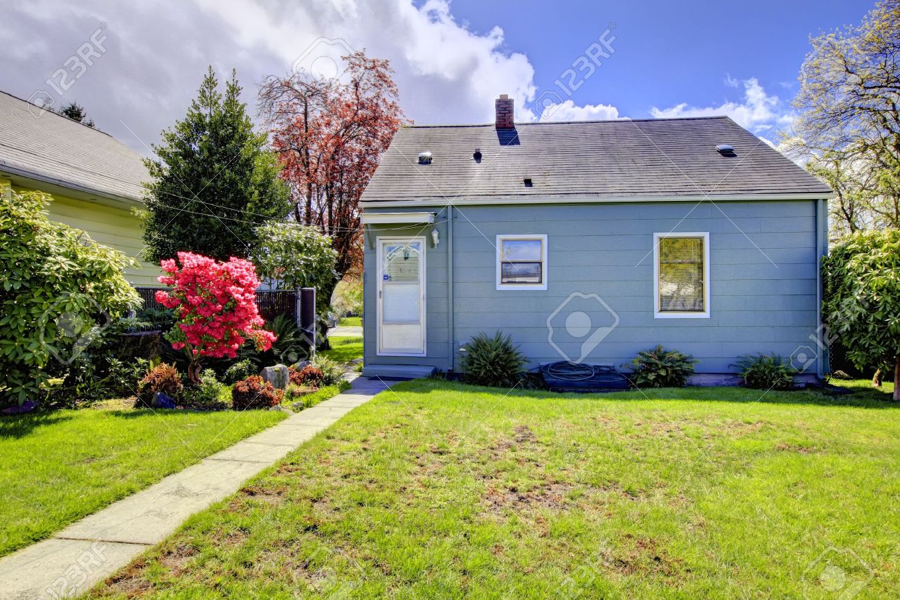 Blue Small House With Spring Landscape From Backyard With Green Blue small house with spring landscape from backyard with green grass. American house build in - Blue Small House With Spring Landscape From Backyard With Green