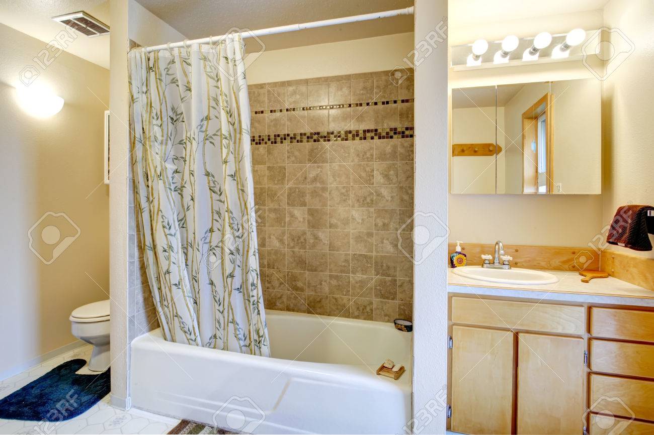archivio fotografico vista della vasca da bagno con tende e muro di piastrelle trim vanity con specchio e wc con la coperta blu