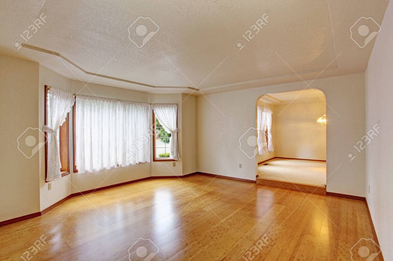 Empty Living Room With Shiny Hardwood Floor And White Curtains
