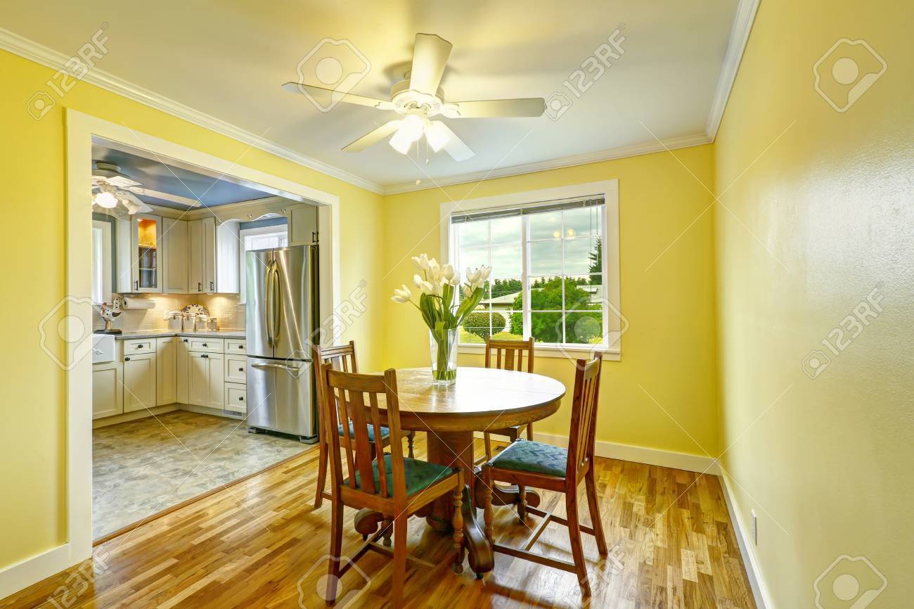 Bright Yellow Dining Room With Wooden Round Table And Chairs Stock Photo
