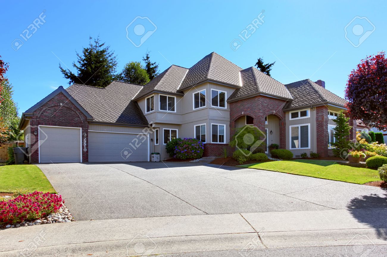 Luxury House Front big luxury house with tile roof and brick trim. view of garage Luxury House Front big luxury house with tile roof and brick trim. view of garage