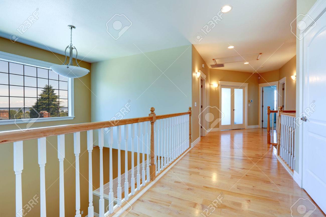 Upstairs Hallway With Shiny Hardwood Floor And White Railings