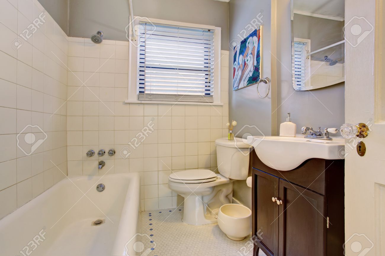 grau antike elegante bad mit weißen wanne, dunkelbraun schrank und weißen  fliesen.