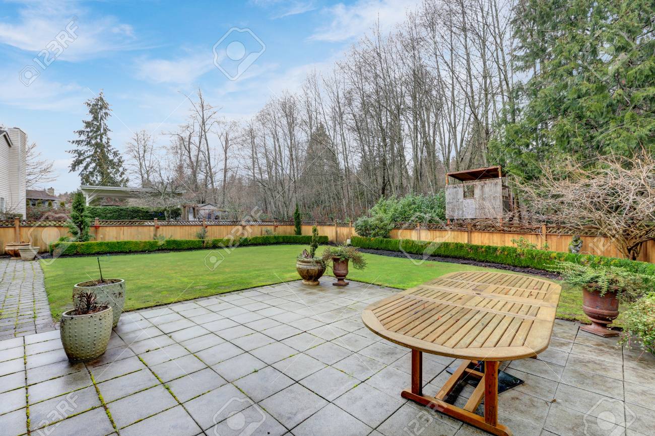 外装のアメリカの植民地の家庭巨大なパティオとよく手入れされた裏庭 パティオ エリアは タイル張りの床の上に大きな木のテーブルを備えています 米国北西部 の写真素材 画像素材 Image