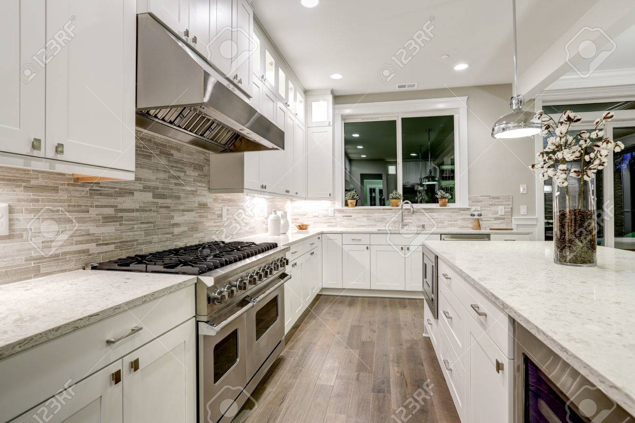 Gourmet kitchen features white shaker cabinets with marble countertops, stone subway tile backsplash and gorgeous kitchen island. Northwest, USA - 72942201 Gourmet kitchen features white shaker cabinets with marble countertops, stone subway tile backsplash and gorgeous kitchen island. Northwest, USA - 72942201