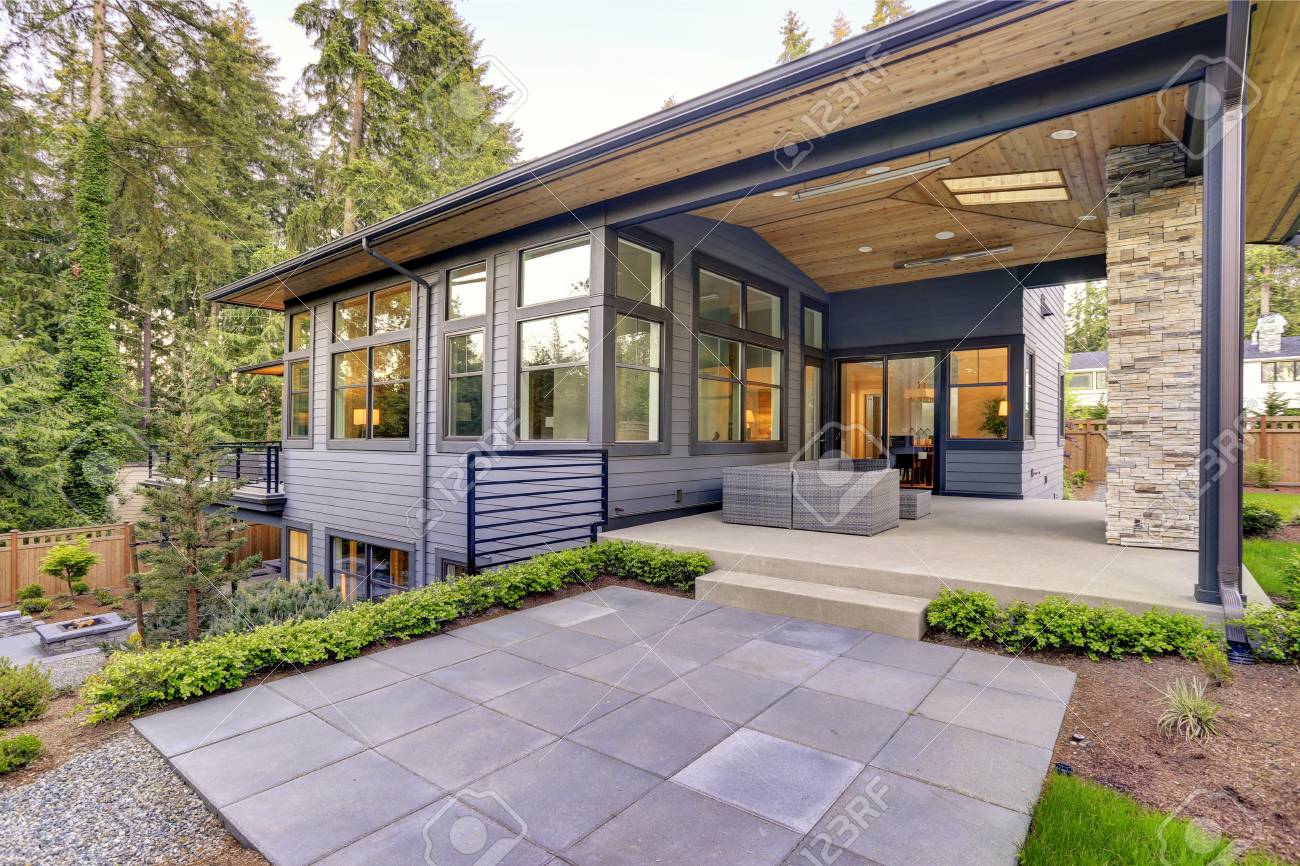 New modern home features a backyard with covered patio accented with stone fireplace, vaulted ceiling with skylights and furnished with gray wicker sofa placed on concrete floor. Northwest, USA - 89705510 New modern home features a backyard with covered patio accented with stone fireplace, vaulted ceiling with skylights and furnished with gray wicker sofa placed on concrete floor. Northwest, USA - 89705510