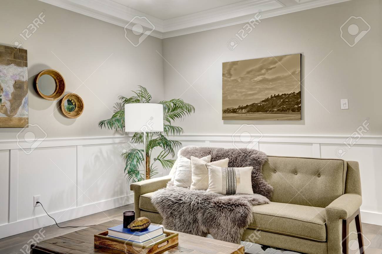 格間 Cealing 付きの素敵な職人スタイルのリビングルームで ボードとバッテンの木製パネルが付いた明るいベージュの壁の上にあります 枕で飾られた快適なソファーとトープの毛布 ノースウェスト アメリカ合衆国 の写真素材 画像素材 Image