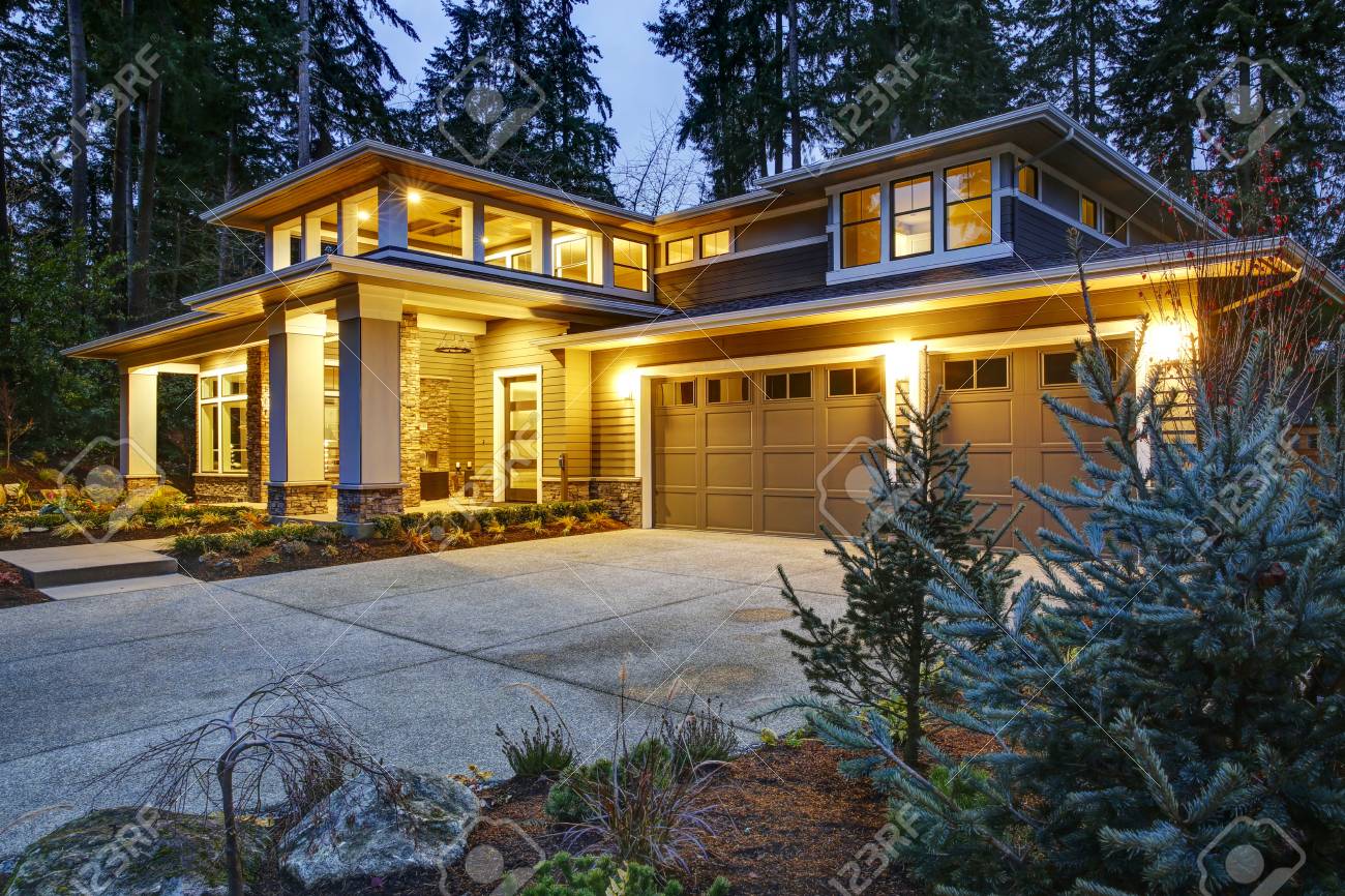 Luxurious new construction home exterior at sunset. View of two garage spaces with concrete driveway and illuminated porch with columns. Northwest, USA - 93635527 Luxurious new construction home exterior at sunset. View of two garage spaces with concrete driveway and illuminated porch with columns. Northwest, USA - 93635527