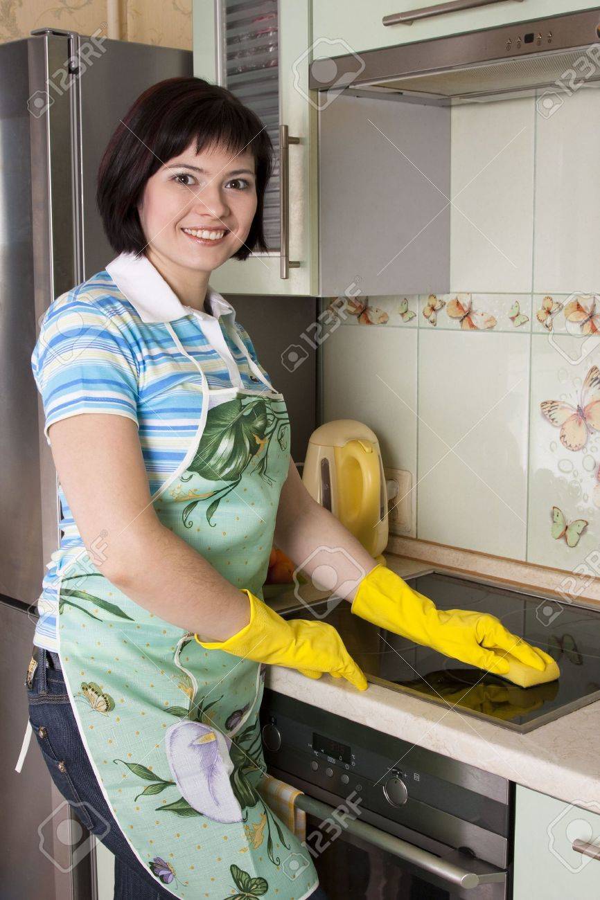 Young woman cleaning cooker at the kitchen. Smiling female washing stove top. - 6833912 Young woman cleaning cooker at the kitchen. Smiling female washing stove top. - 6833912