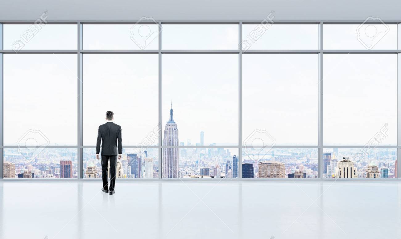 thoughtful businessman looking out window in bright office interior window office