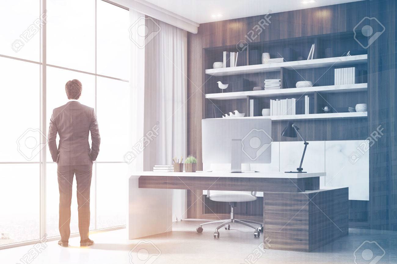rear view of a company ceo standing in his dark wood office with dark wood office