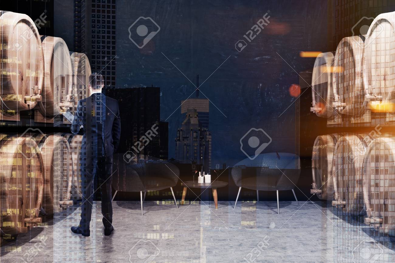 Man With Folder Standing In Black Brick Wine Cellar With A