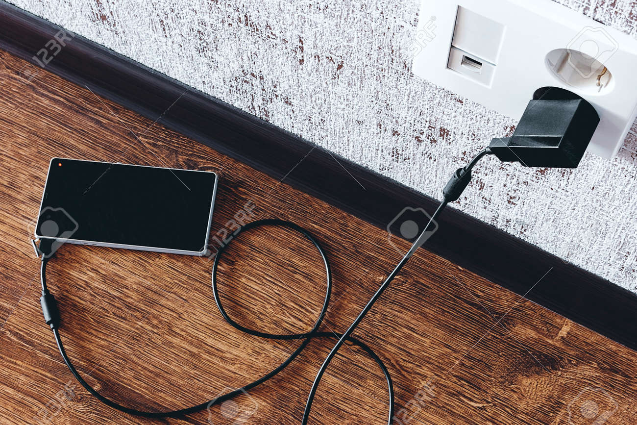 phone charging in the apartment on the floor - 166172180 phone charging in the apartment on the floor - 166172180
