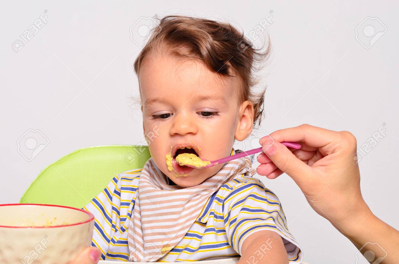 赤ちゃんスプーン 汚い汚いと取得を食べる幼児 幼児の朝食 親の手が彼の子供を餌としてオートミールを持つ食べ物 の写真素材 画像素材 Image