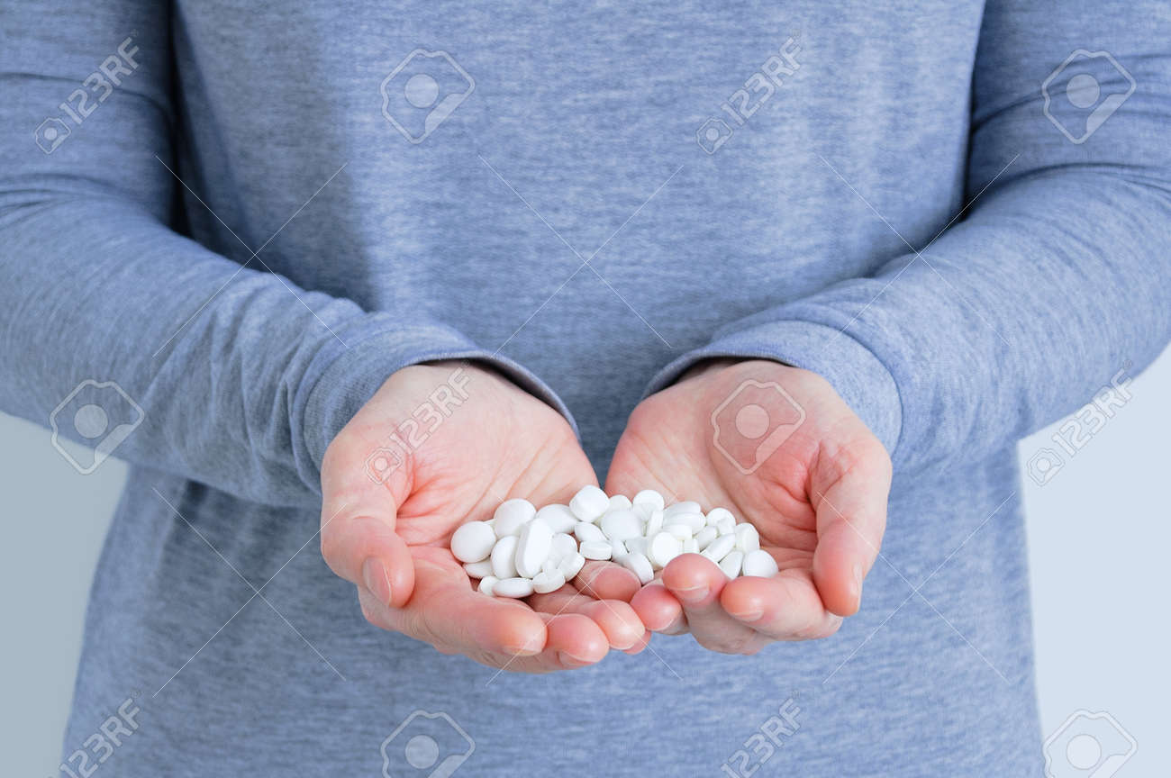 A handful of white pills on the palms of a Caucasian woman close-up. - 171610456 A handful of white pills on the palms of a Caucasian woman close-up. - 171610456