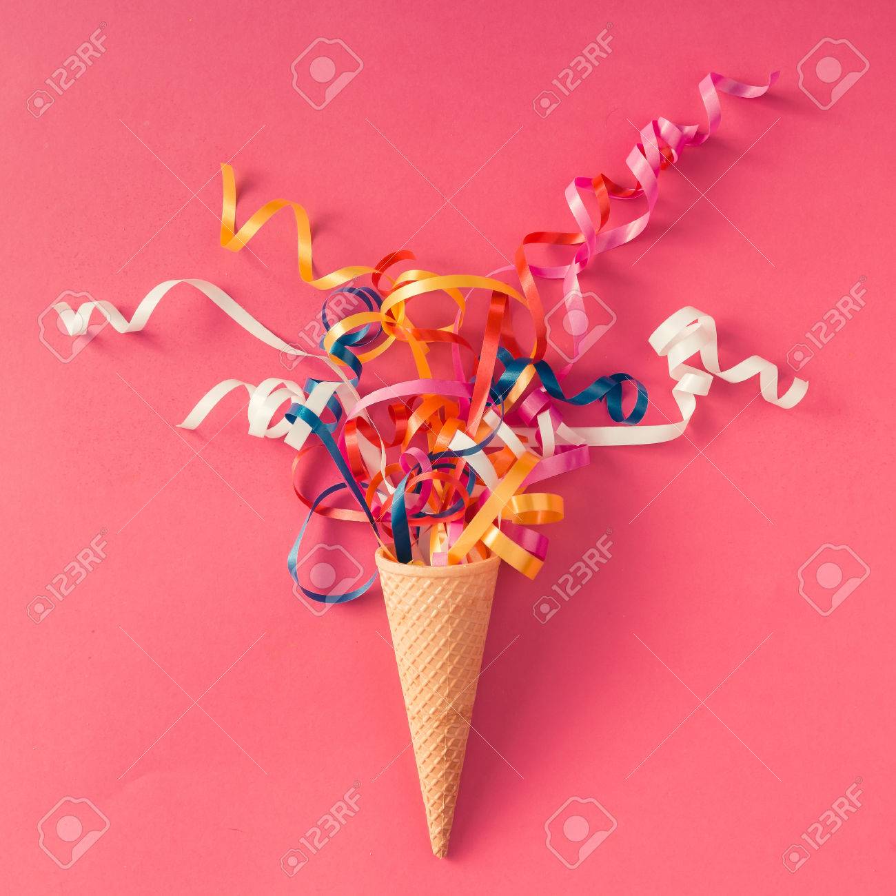 Ice cream cone with colorful party streamers on pink background. Flat lay - 71523109 Ice cream cone with colorful party streamers on pink background. Flat lay - 71523109