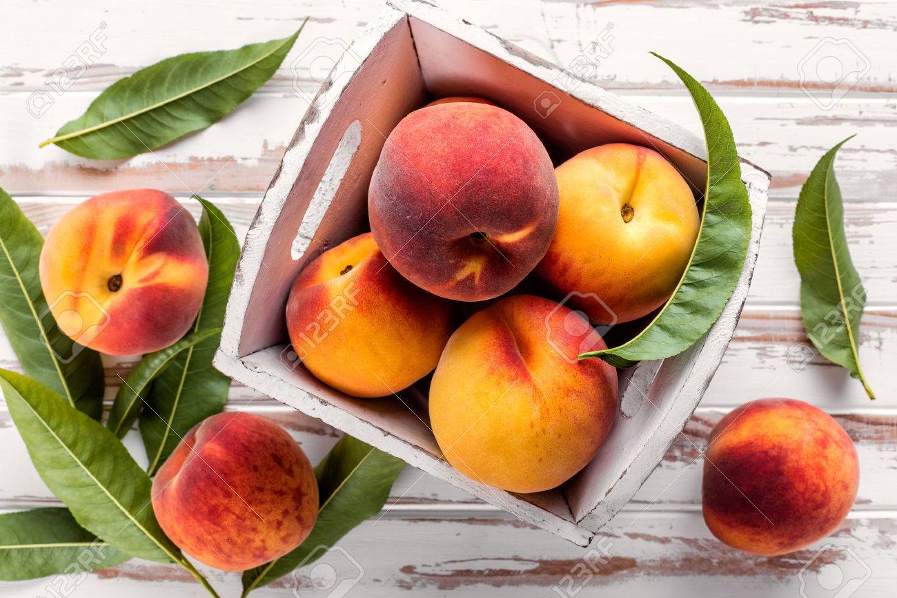 fresh peaches with leaves on white wooden table top view - 61699454 fresh peaches with leaves on white wooden table top view - 61699454