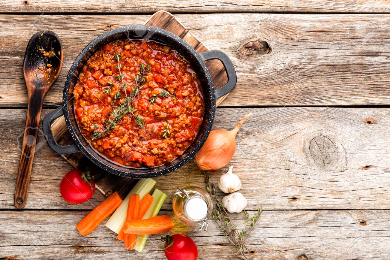 classic italian bolognese sauce stewed in cauldron with ingredients on wooden table, top view, culinary background with space for text - 97027682 classic italian bolognese sauce stewed in cauldron with ingredients on wooden table, top view, culinary background with space for text - 97027682