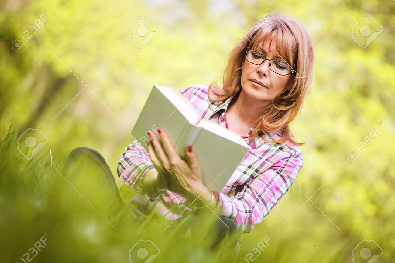 熟女　魅力 美しい熟女。魅力的な熟女が公園で本を読んでします。の写真素材・画像素材 Image 67879234