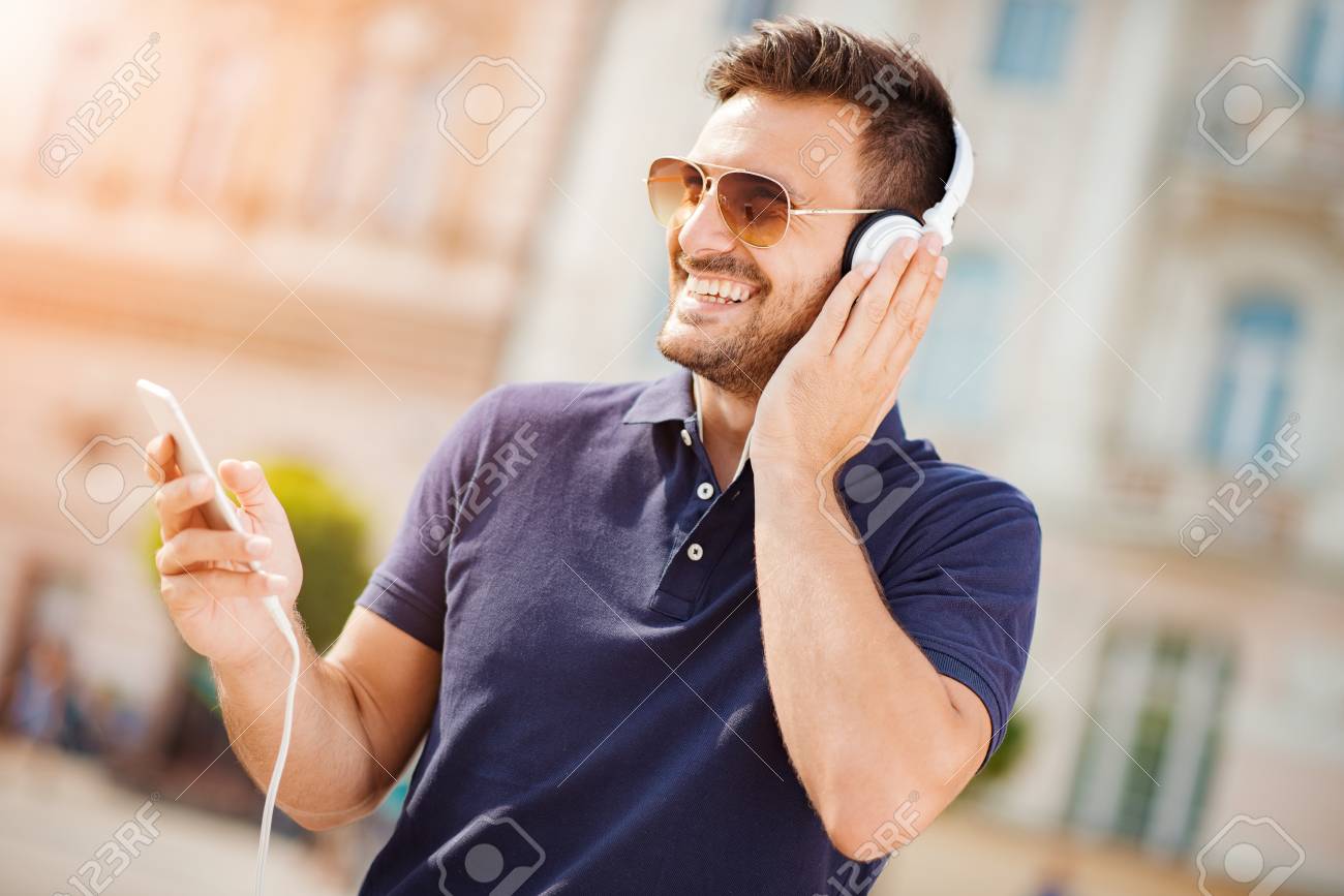 young man listening to music on a smart phone he is listening