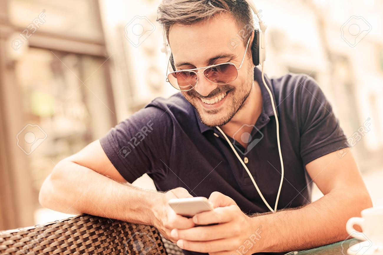 young man listening to music on a smart phone he is listening
