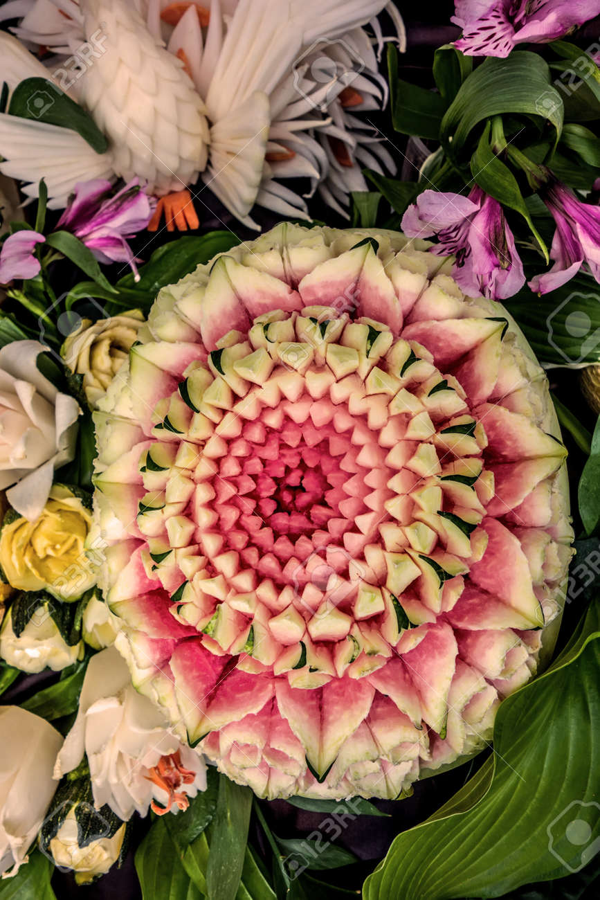 Culinary Carving From Vegetables And Fruits. Beautiful Pink Flower Cut From  A Watermelon On A Background Of Green Leaves And Flowers. Carved Watermelon  Fruit. Stock Photo, Picture and Royalty Free Image. Image, image size:867x1300