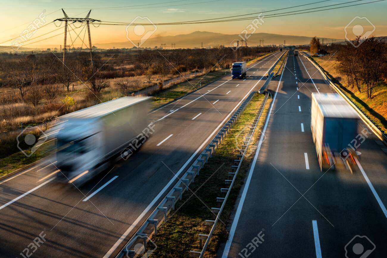 Delivery trucks in high speed driving on a highway through rural landscape. Fast blurred motion drive on the freeway. Freight scene on the motorway - 137407864 Delivery trucks in high speed driving on a highway through rural landscape. Fast blurred motion drive on the freeway. Freight scene on the motorway - 137407864