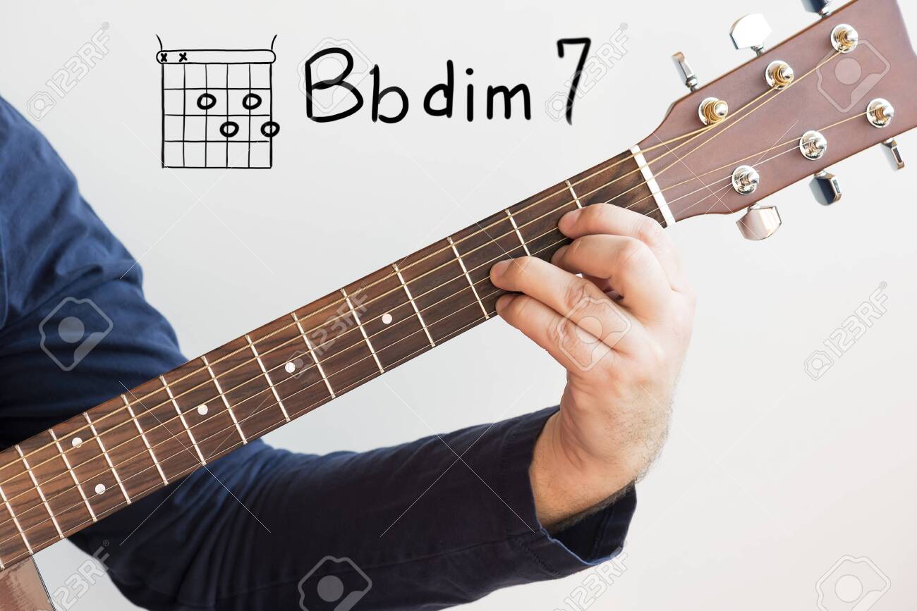 Learn Guitar Man In A Dark Blue Shirt Playing Guitar Chords Displayed On Whiteboard Chord B Flat Dim 7 Stock Photo Picture And Royalty Free Image Image
