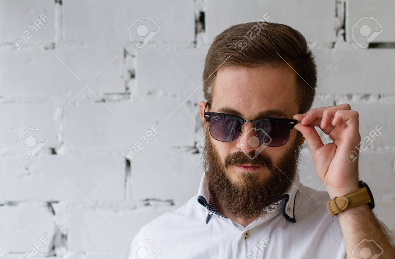 ひげと白いレンガの壁の前でサングラスに髭の若い男 の写真素材 画像素材 Image