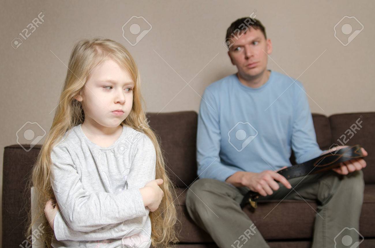 Foto de archivo - Niña aterrorizada desde el castigo físico de su padre con un cinturón