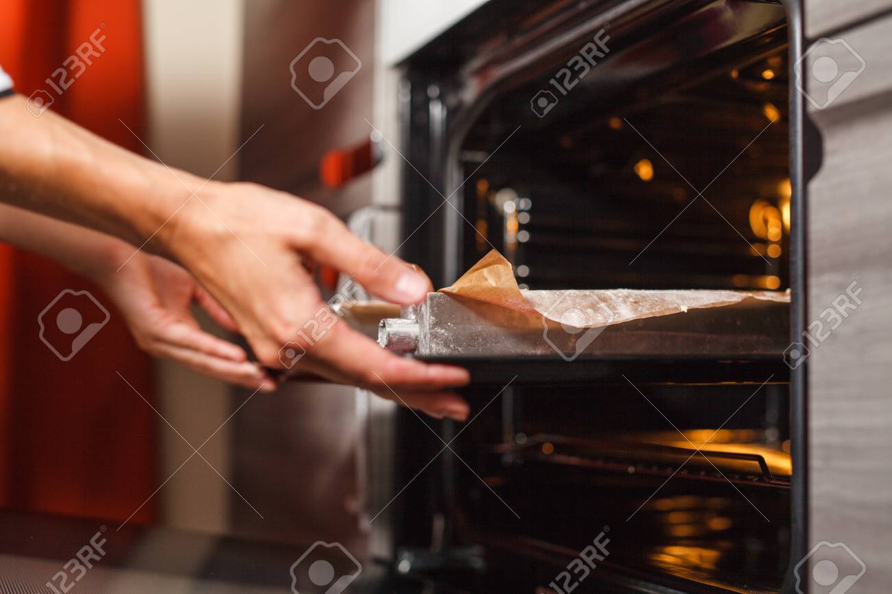 Femme faisant la cuisine dans la cuisine, met les gâteaux au four - 72007201