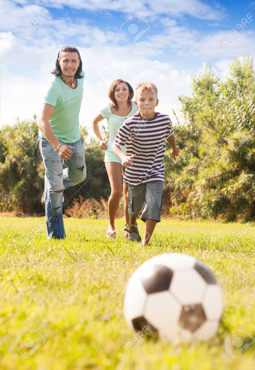 夏の公園でサッカー ボールと遊ぶ息子と幸せなカップル の写真素材 画像素材 Image