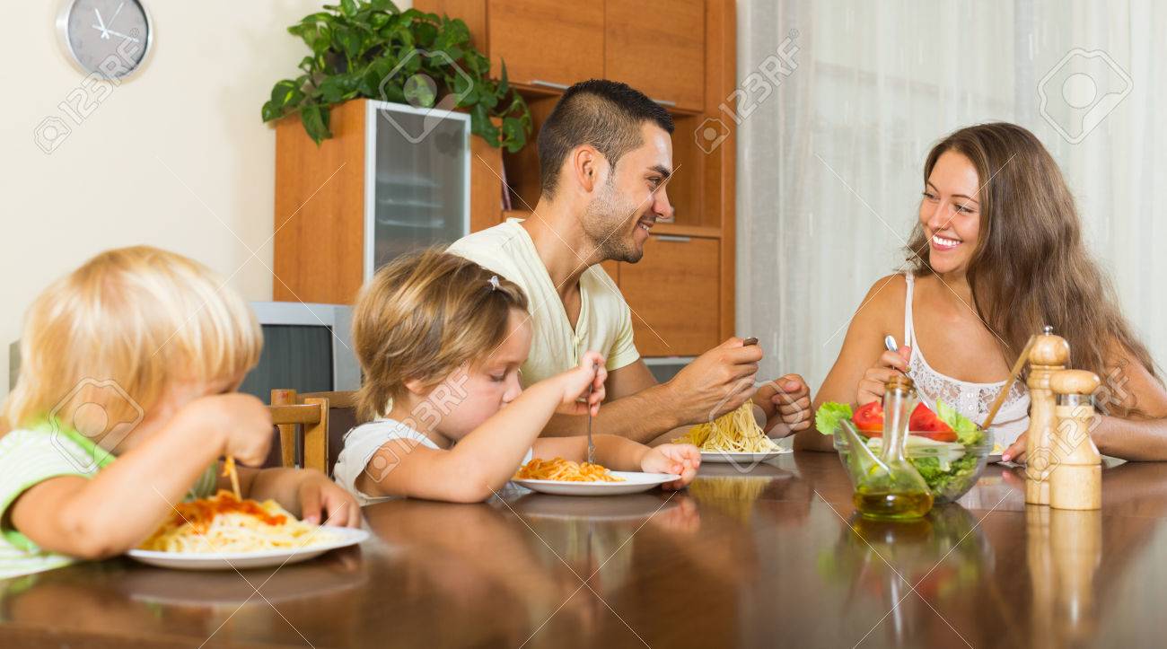 Happy Family Of Four Eating Pasta At Home Together Stock Photo Picture And Royalty Free Image Image