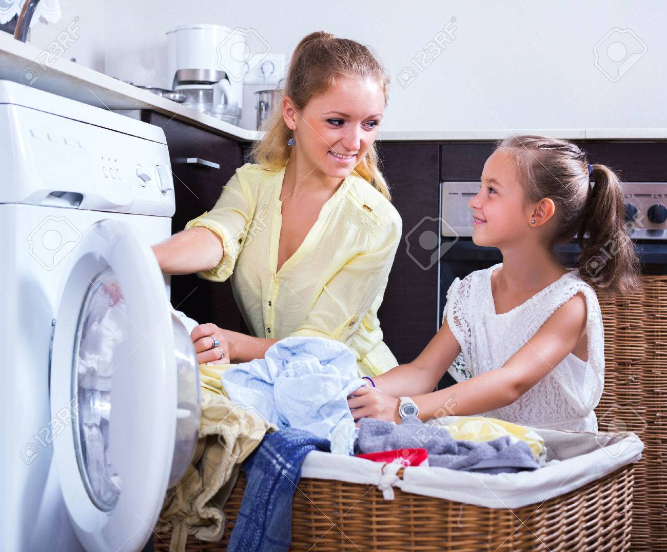 Young housewife and little girl doing laundry together - 51353226 Young housewife and little girl doing laundry together - 51353226