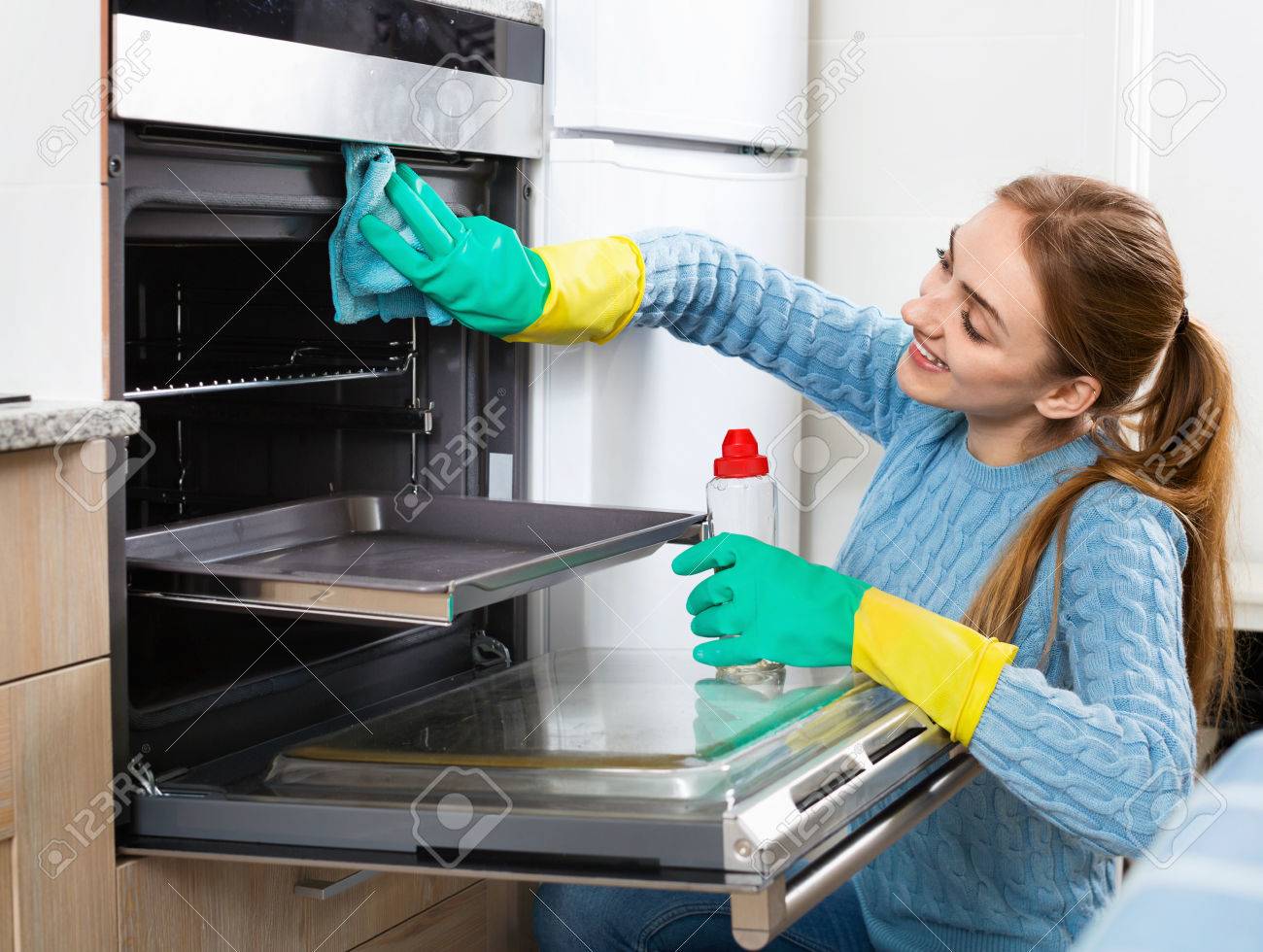 Cheerful positive adult girl in gloves removing snuff in oven - 55094843 Cheerful positive adult girl in gloves removing snuff in oven - 55094843