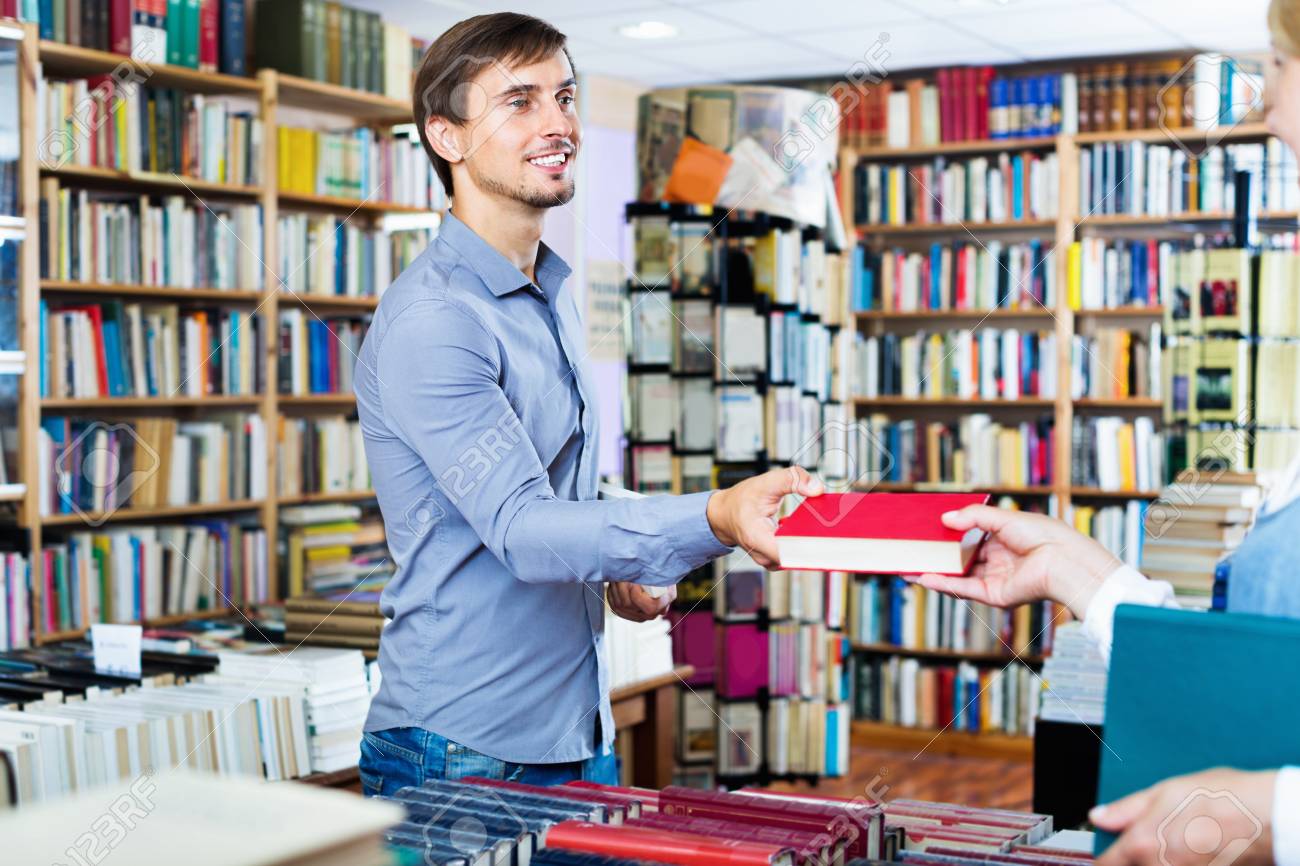 Человек выбирает книгу. Мужчина у книжной полки. Девушка в библиотеке. Студенты в библиотеке. Девушка поднимает книгу.