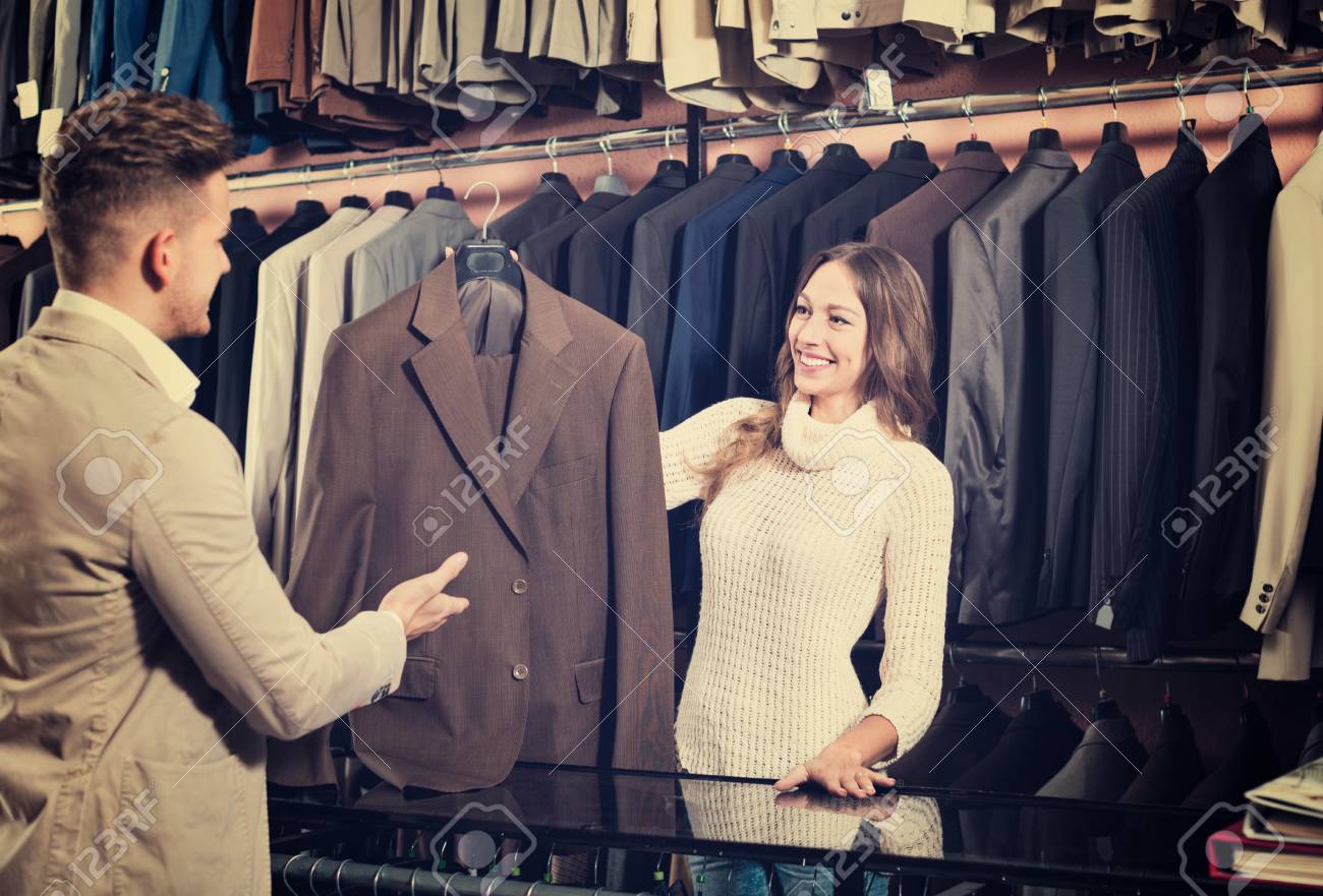陽気な女性店員の紳士服店でスーツを選択する顧客を支援 の写真素材 画像素材 Image