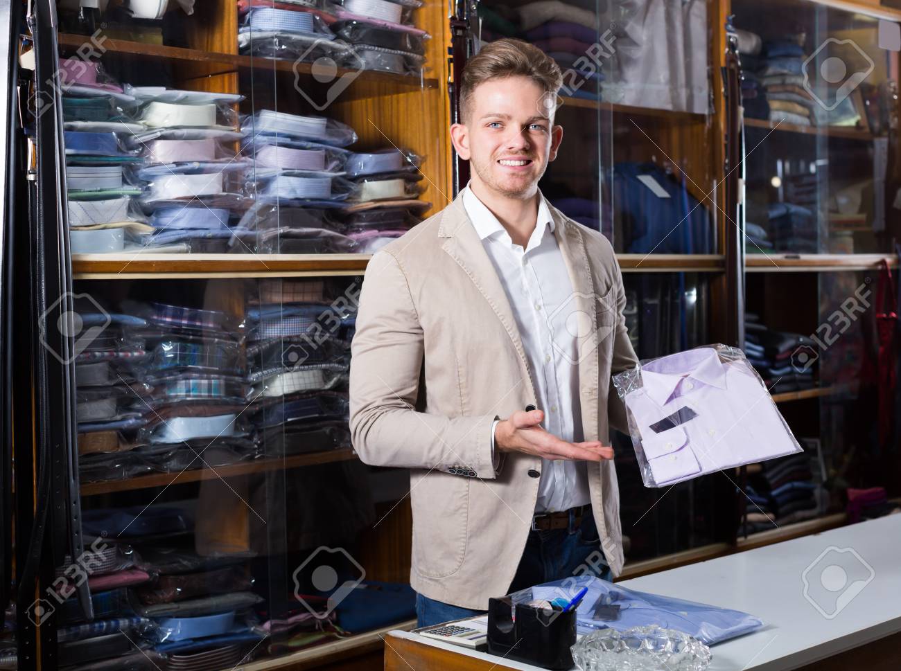 Asistente De Compras Masculino Feliz Que Diversas Camisas En La Tienda De Paños De Los Hombres Fotos, Retratos, Imágenes Fotografía De Archivo Libres De Derecho. Image 69170782.
