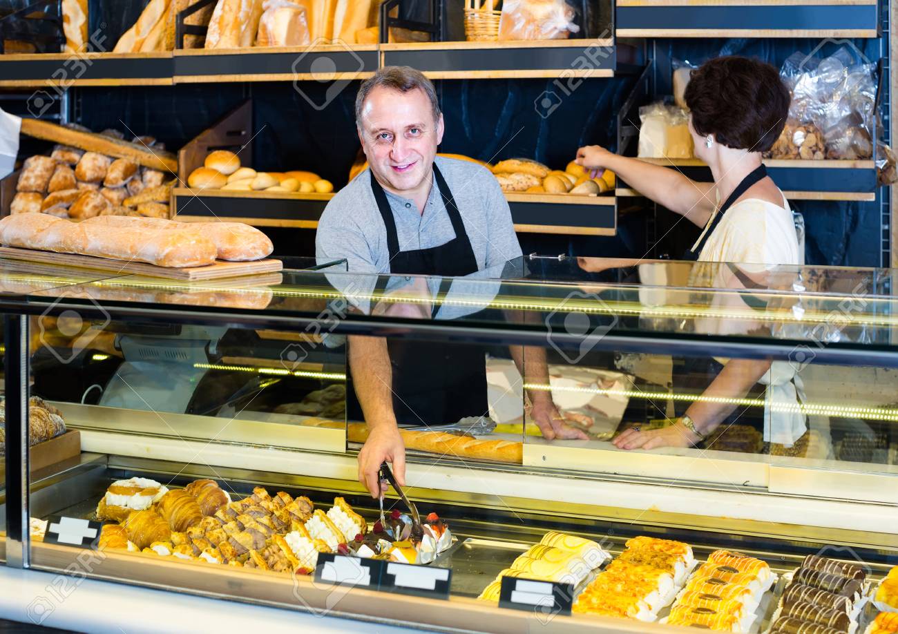 新鮮なバゲットとパン屋さんのパンを提供する幸せなアメリカ人スタッフ の写真素材 画像素材 Image