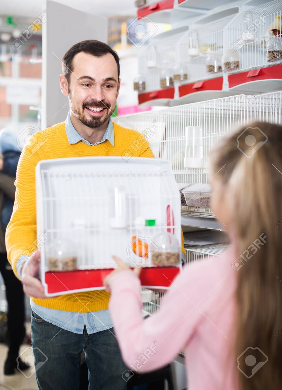 Souriant Vendeur Homme Anglais Démontrant Oiseau Canari Dans La Cage à La Fille Dans Lanimalerie