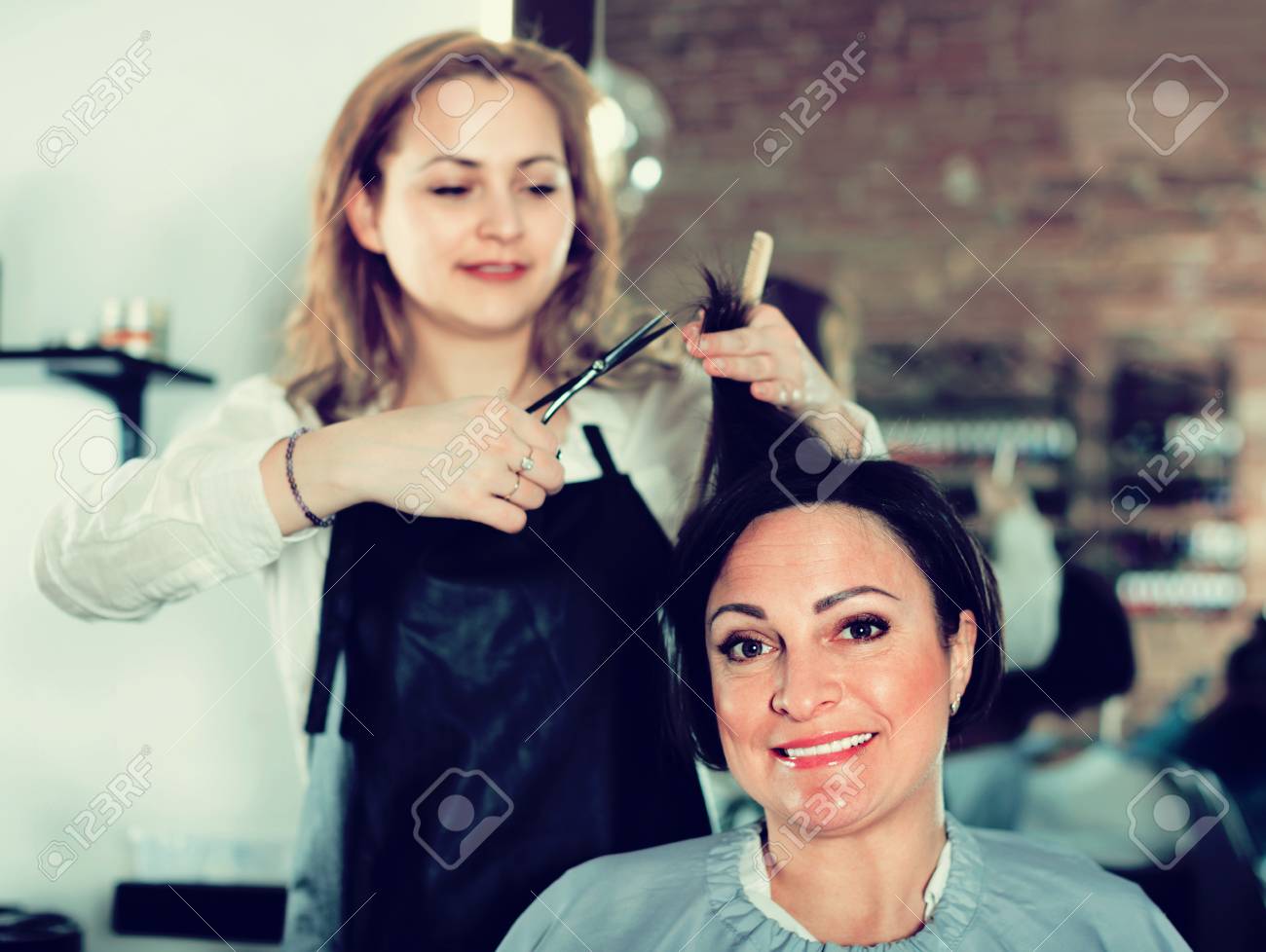 Jeune Coiffeur Positif Gai Fait A La Coupe De Cheveux Femme Avec L