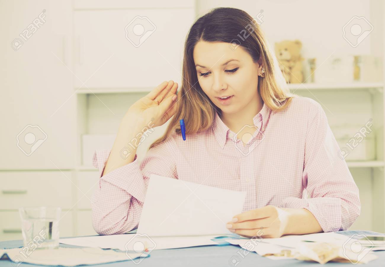 happy girl signing agreement papers of financial nature at home