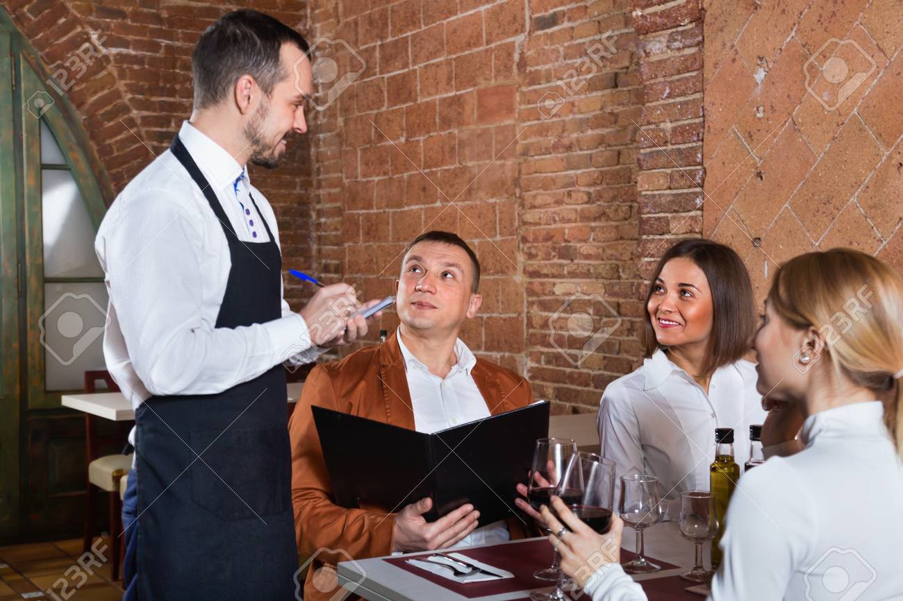 Male waiter taking order from visitors in country restaurant - 90459241 Male waiter taking order from visitors in country restaurant - 90459241