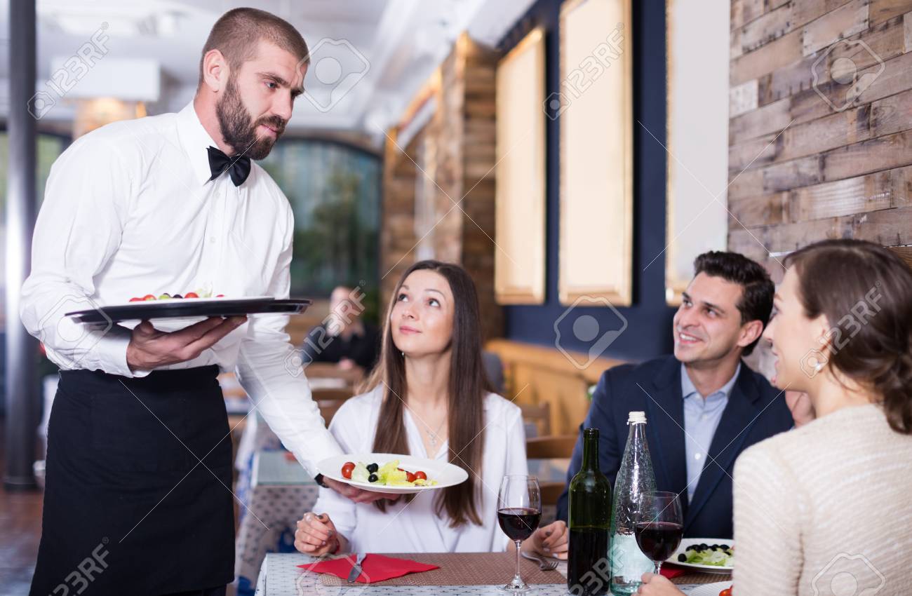 92841670-waiter-worker-male-bringing-food-for-people-of-adult-smiling-visitors.jpg