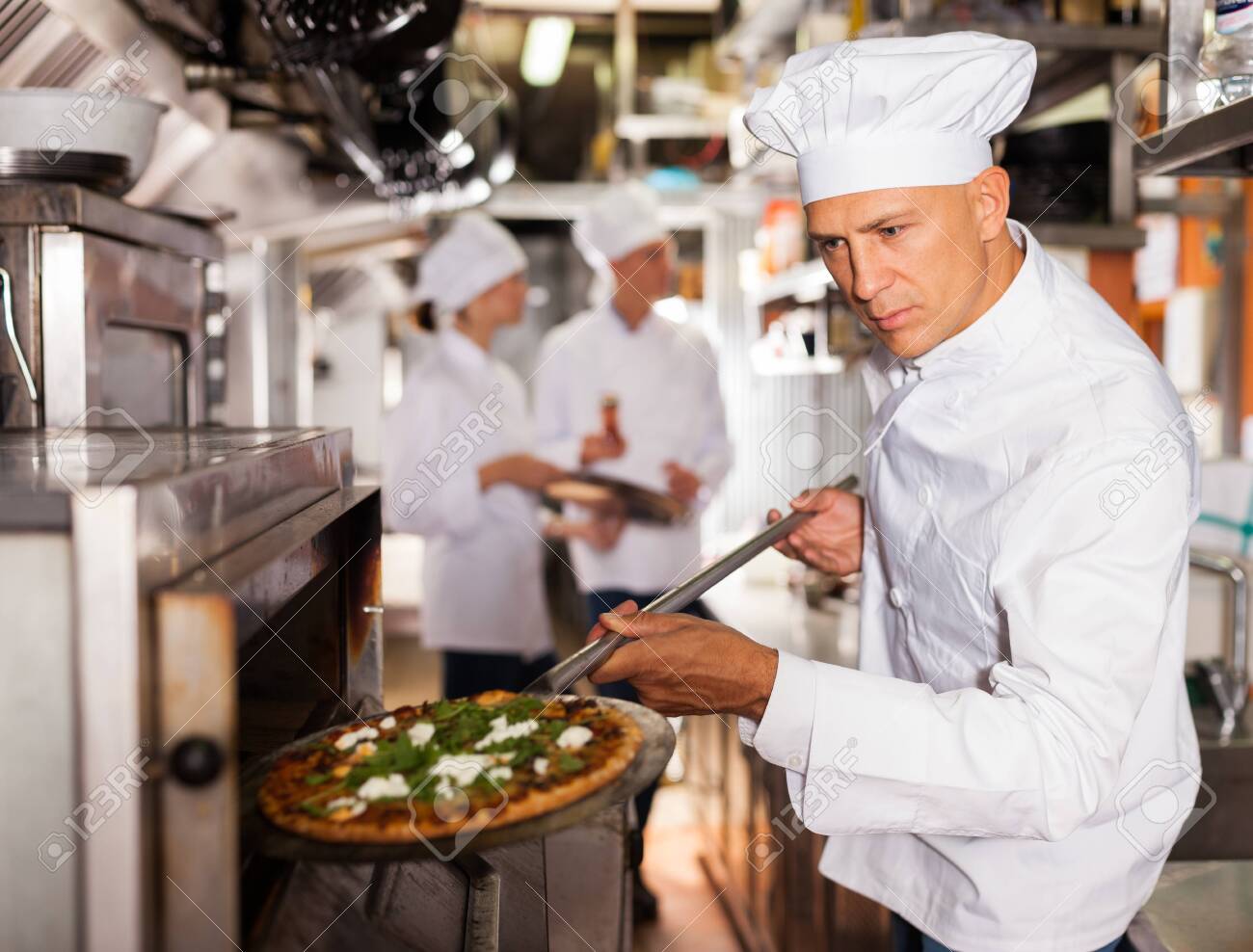 skilled male chef in white uniform working in professional kitchen restaurant working